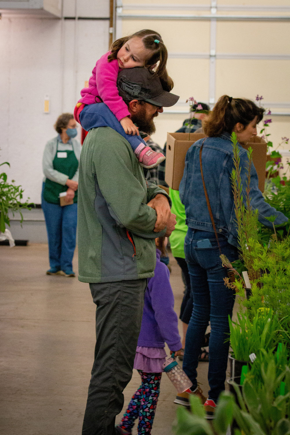 A tired little girl sits on her father’s shoulders at the Master Gardener Plant Sale at the Southwest Washington Fairgrounds.